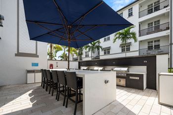 A kitchen with a bar and chairs under an umbrella